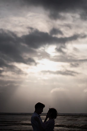 A sweeping outdoor scene at dusk with the couple silhouetted against a dramatic sky.