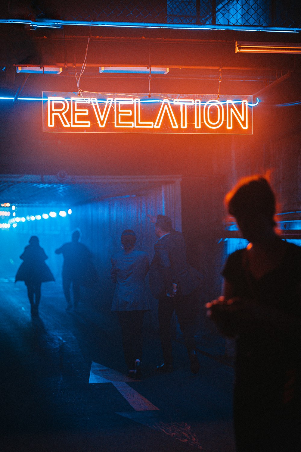 a group of people standing under a neon sign