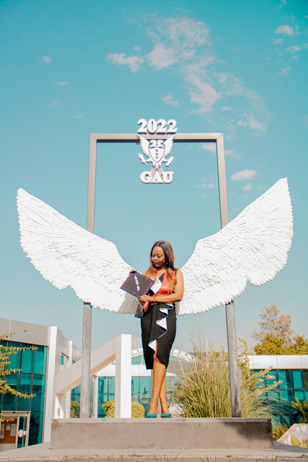 a woman standing in front of a large angel statue