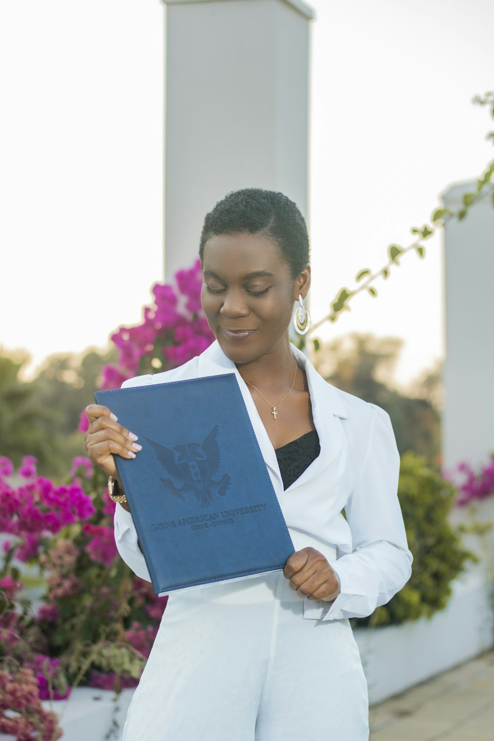 a woman in a white suit holding a blue book