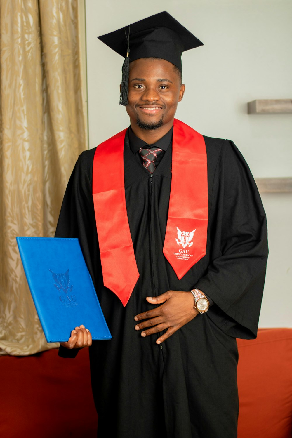 a man in a graduation gown holding a blue folder