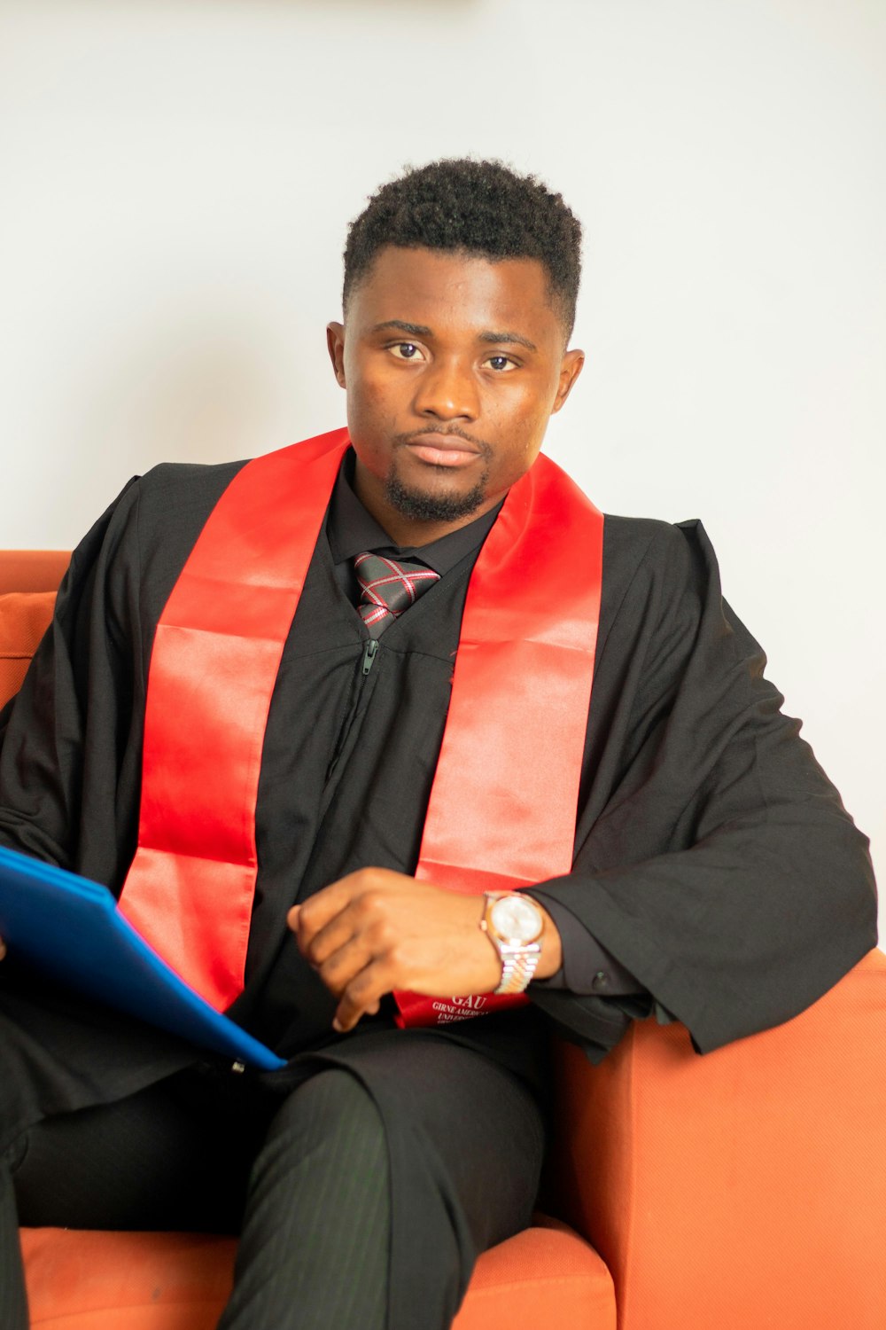 a man in a graduation gown sitting on a couch