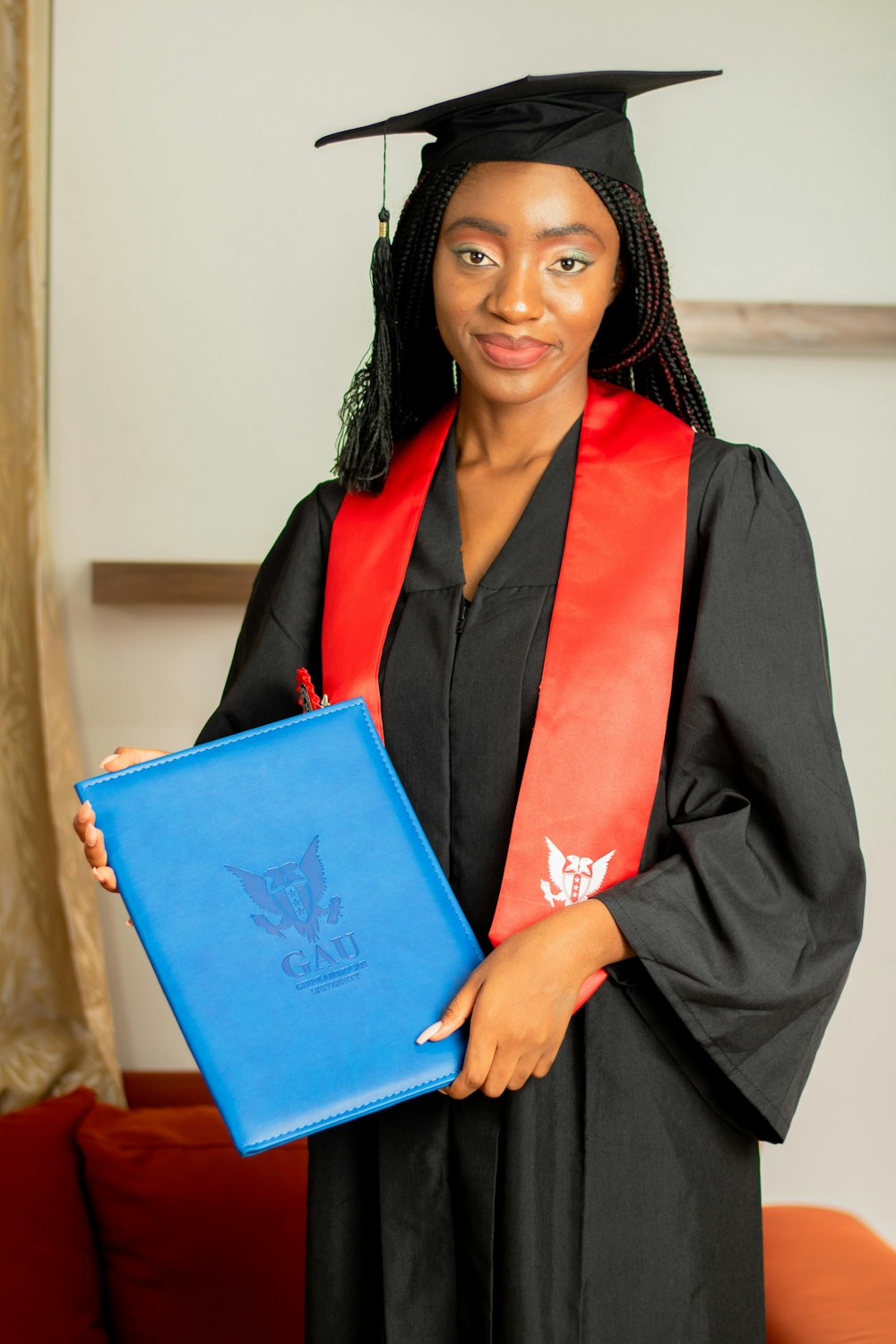 a woman in a graduation gown holding a blue folder