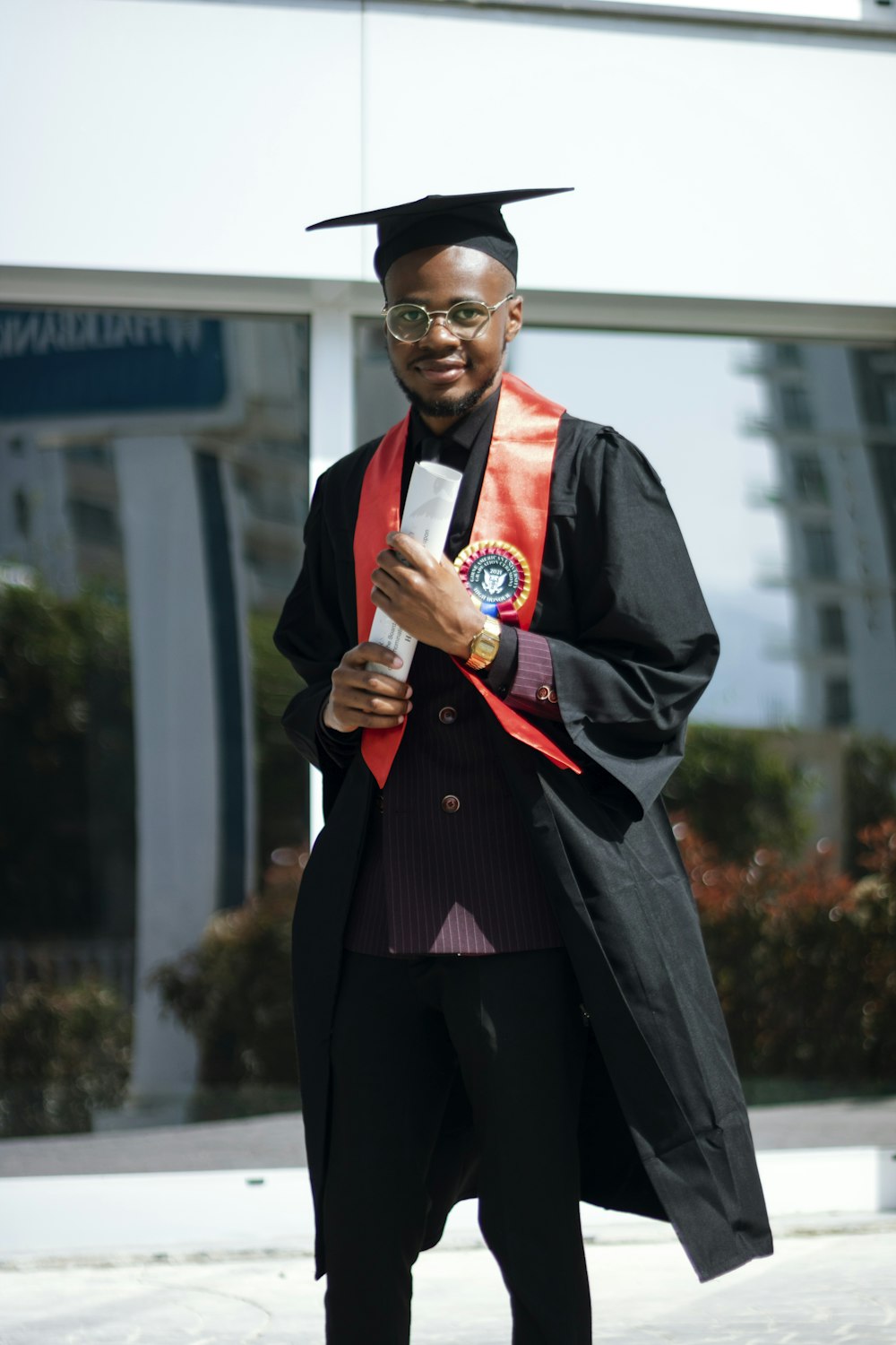 a man in a graduation gown holding a cell phone