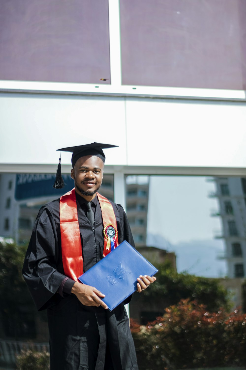 a man in a cap and gown holding a blue folder