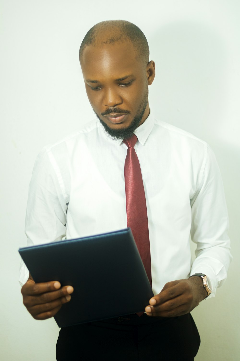 a man in a white shirt and red tie looking at a laptop