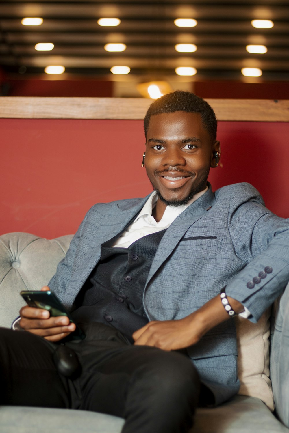 a man sitting on a couch holding a cell phone