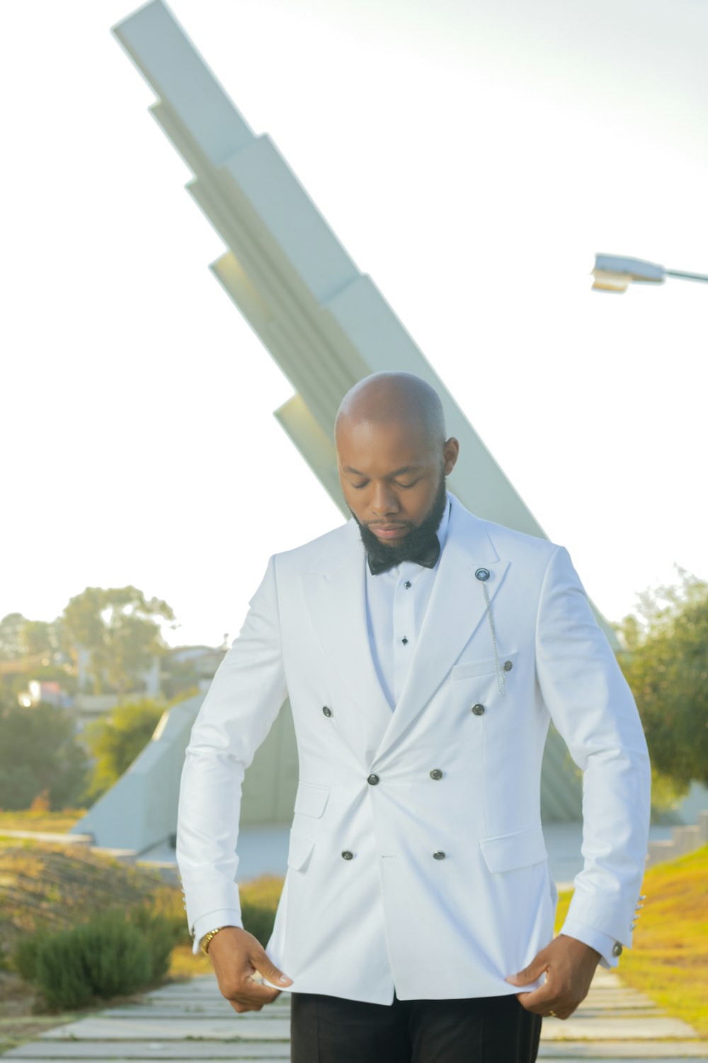 a man in a white tuxedo standing on a sidewalk