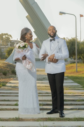 A bride and groom in custom formal wear posing outdoors on their wedding day
