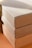 A stack of cardboard boxes with visible seams and edges, arranged in an orderly manner with sunlight casting soft shadows.