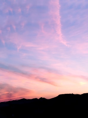 Soft pink and purple clouds stretching over a quiet plateau valley