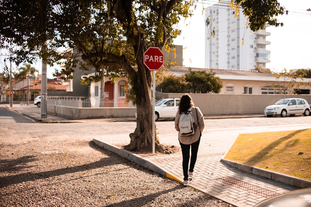 a woman walking down a sidewalk next to a stop sign