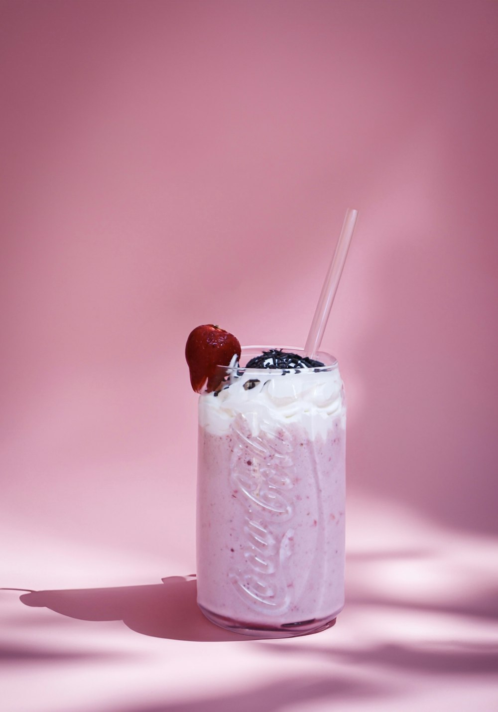 a strawberry milkshake with whipped cream and a straw