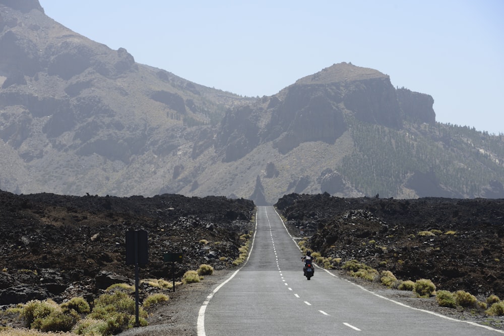 a person riding a motorcycle down the middle of a road