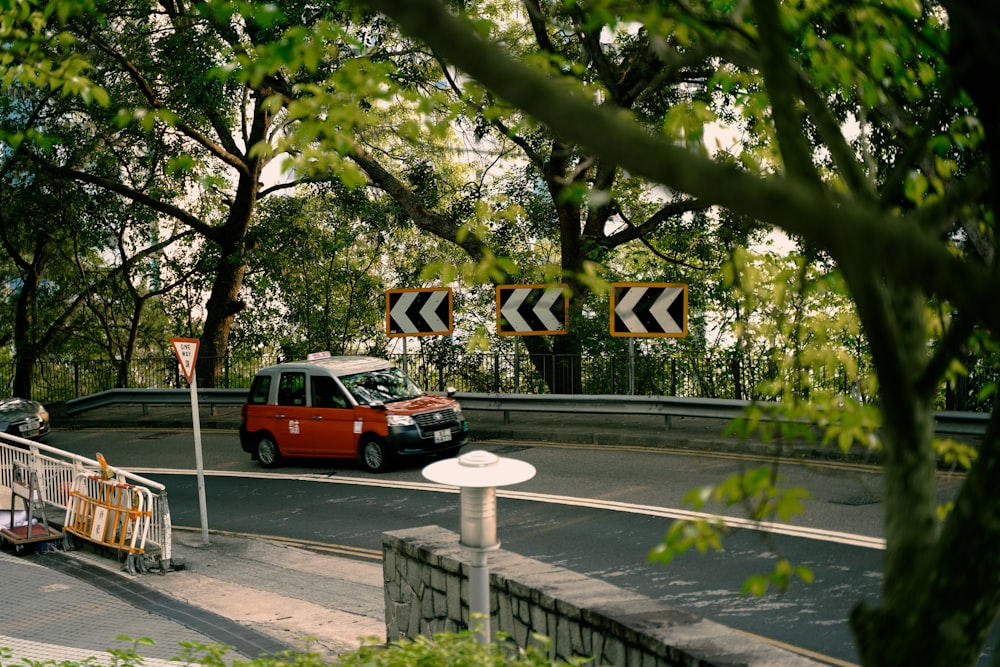 a red car driving down a street next to a street sign