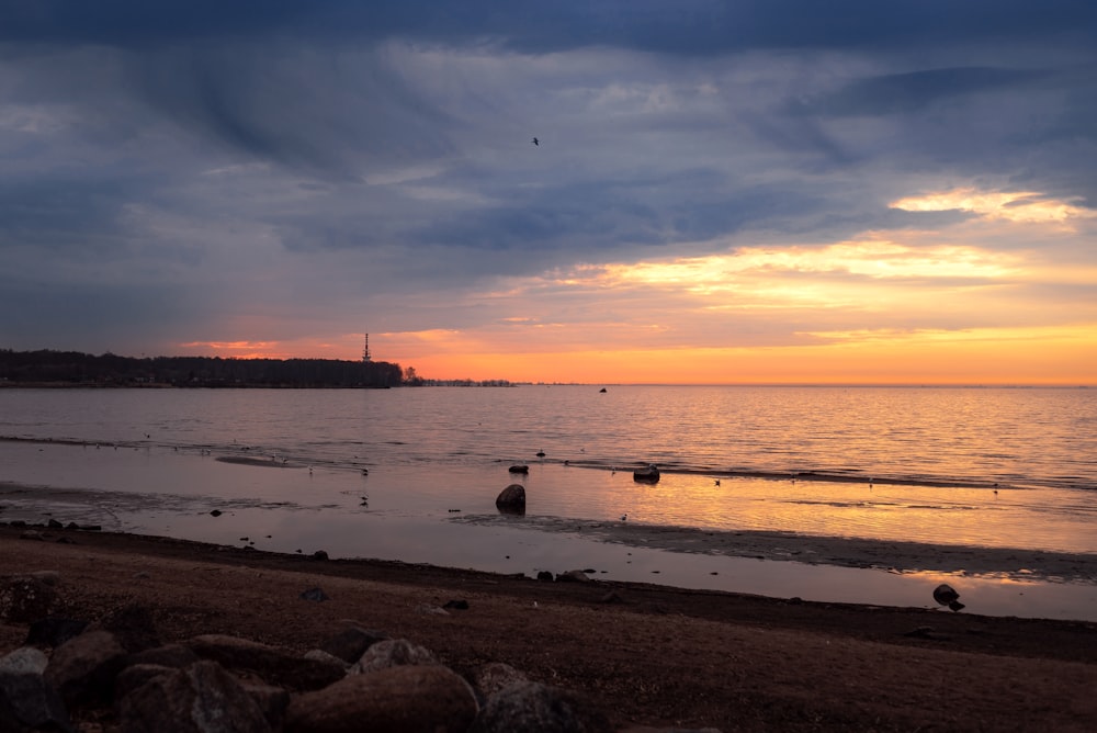 the sun is setting over the water at the beach