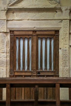 A wooden door with vertical slats is set within an ornate stone frame. The frame features intricate carvings and a textured surface.