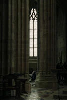 A quiet moment in the basilica’s interior, with a single visitor seated in contemplation beneath the stained glass.
