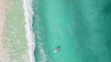 Close-up aerial photo of a paddleboarder gliding on crystal-clear water in Rio das Ostras