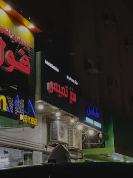 A vibrant storefront sign glowing at dusk in Sharjah Industrial Area 12.
