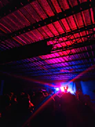 Grainy high-contrast shot of a crowded immersive listening party bathed in shadows and light.