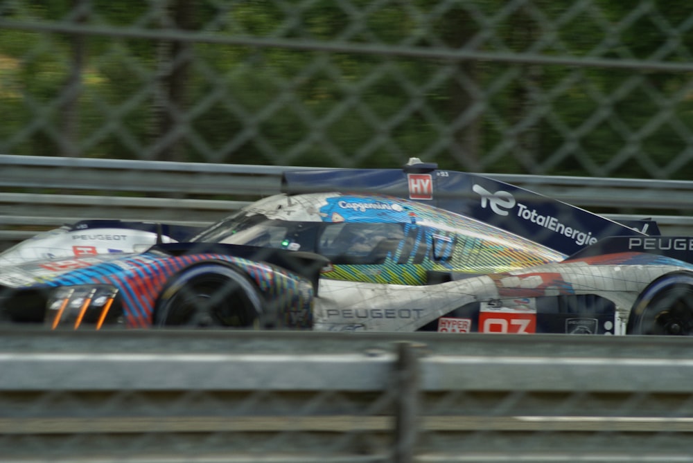 a race car driving on a track through a fence