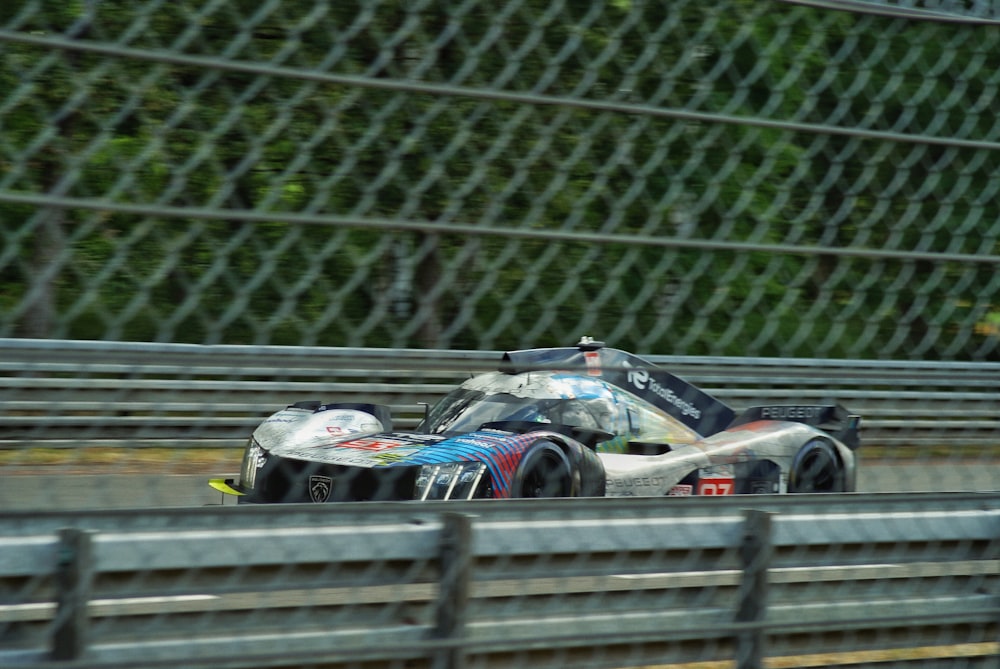 a race car driving on a track near a fence