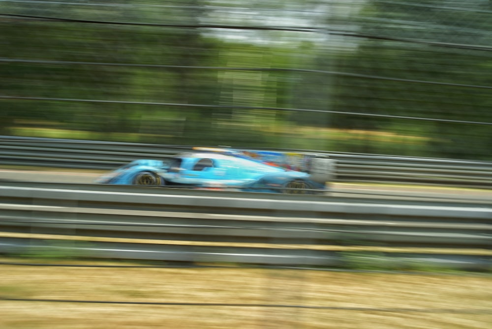 a blue race car driving down a track