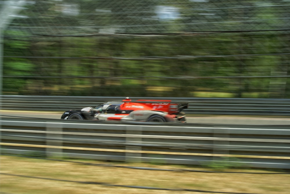 a race car driving on a track with trees in the background