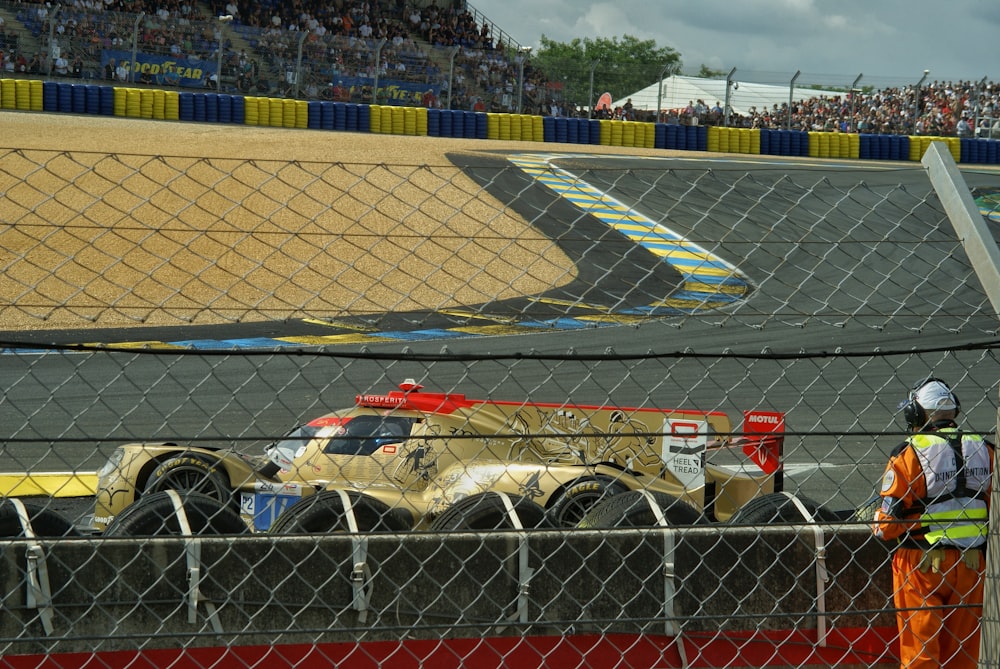 a man standing next to a car on a race track