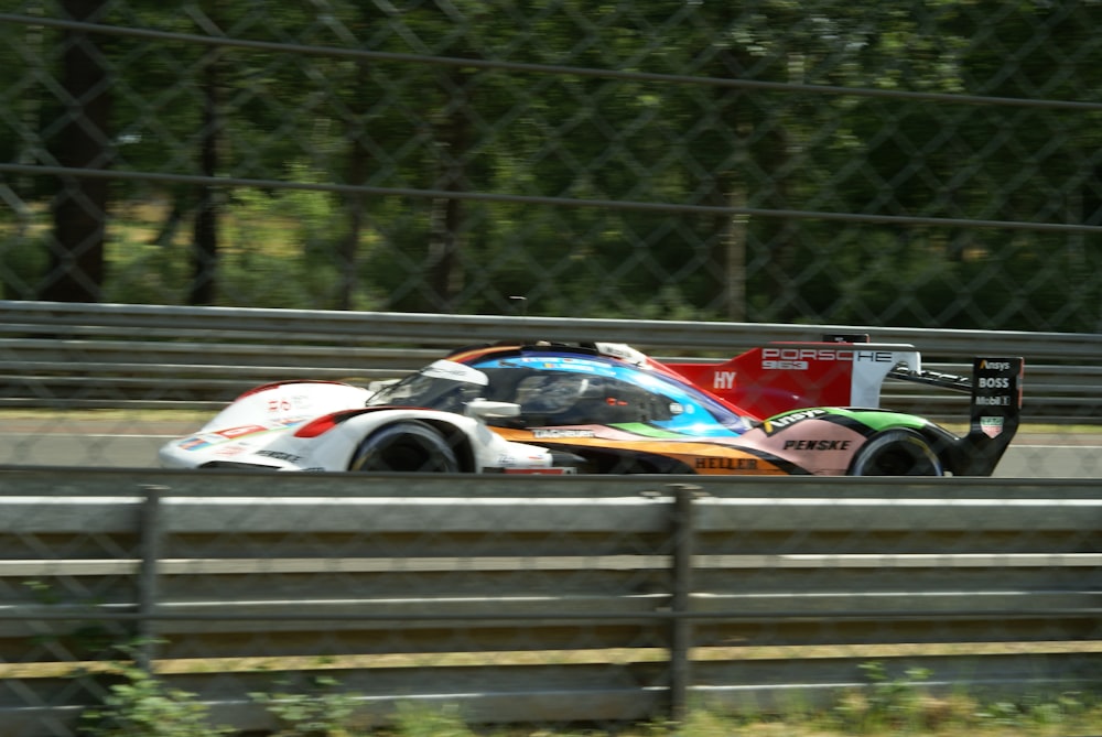 a race car driving on a track with trees in the background