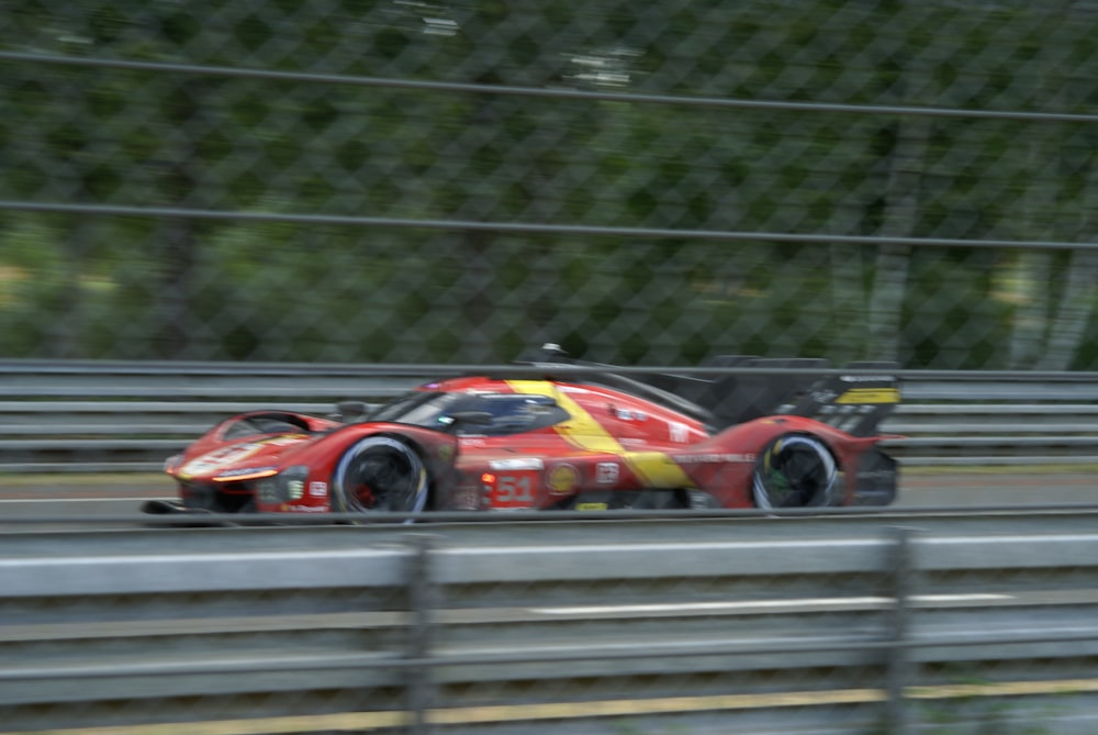 a race car driving on a track behind a fence