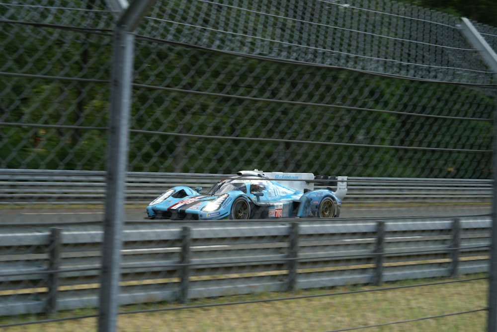 a blue race car driving down a race track