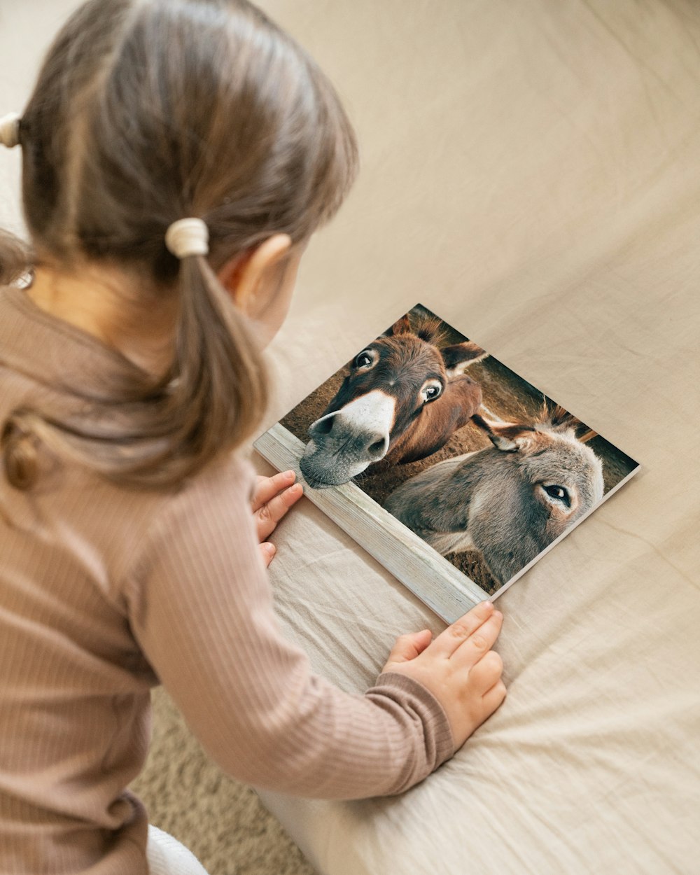 a little girl sitting on a bed reading a book