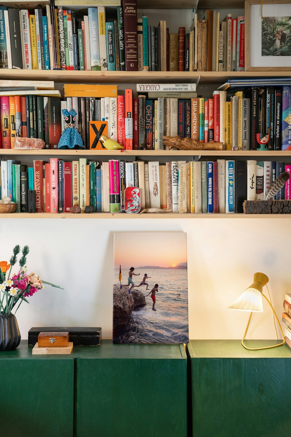 a bookshelf filled with lots of books next to a lamp