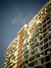 A modern apartment building with clean lines and balconies, bathed in warm sunlight.