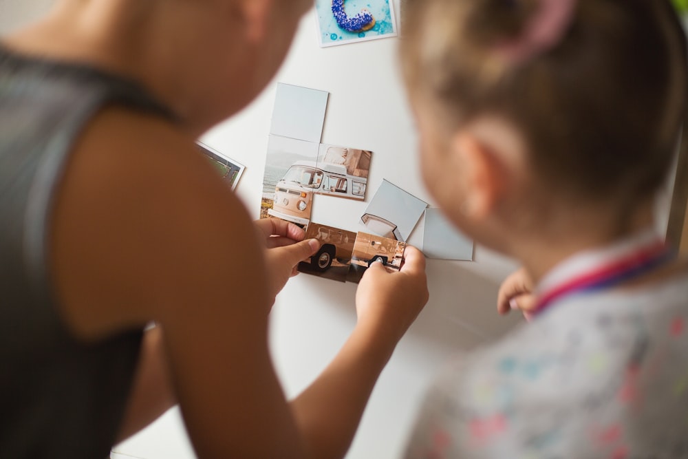 a little girl holding up a picture of a house