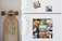 A white refrigerator decorated with multiple animal-themed photographs. The top section features two smaller images of a dog in a forest and a tabby cat. The lower section displays a collage of several animals including ducklings, a rabbit, geese, turkeys, cows, pigs, a goat, a chicken, and a horse. To the left of the fridge, a longboard with stylized text is leaning against the wall.