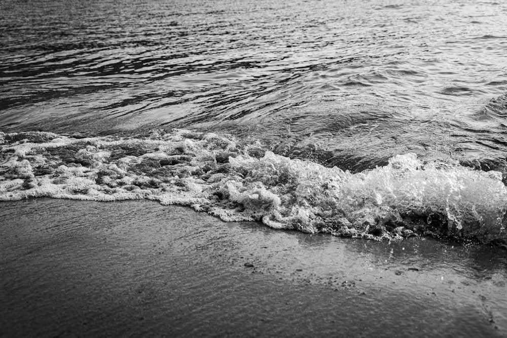 a black and white photo of waves crashing on the beach