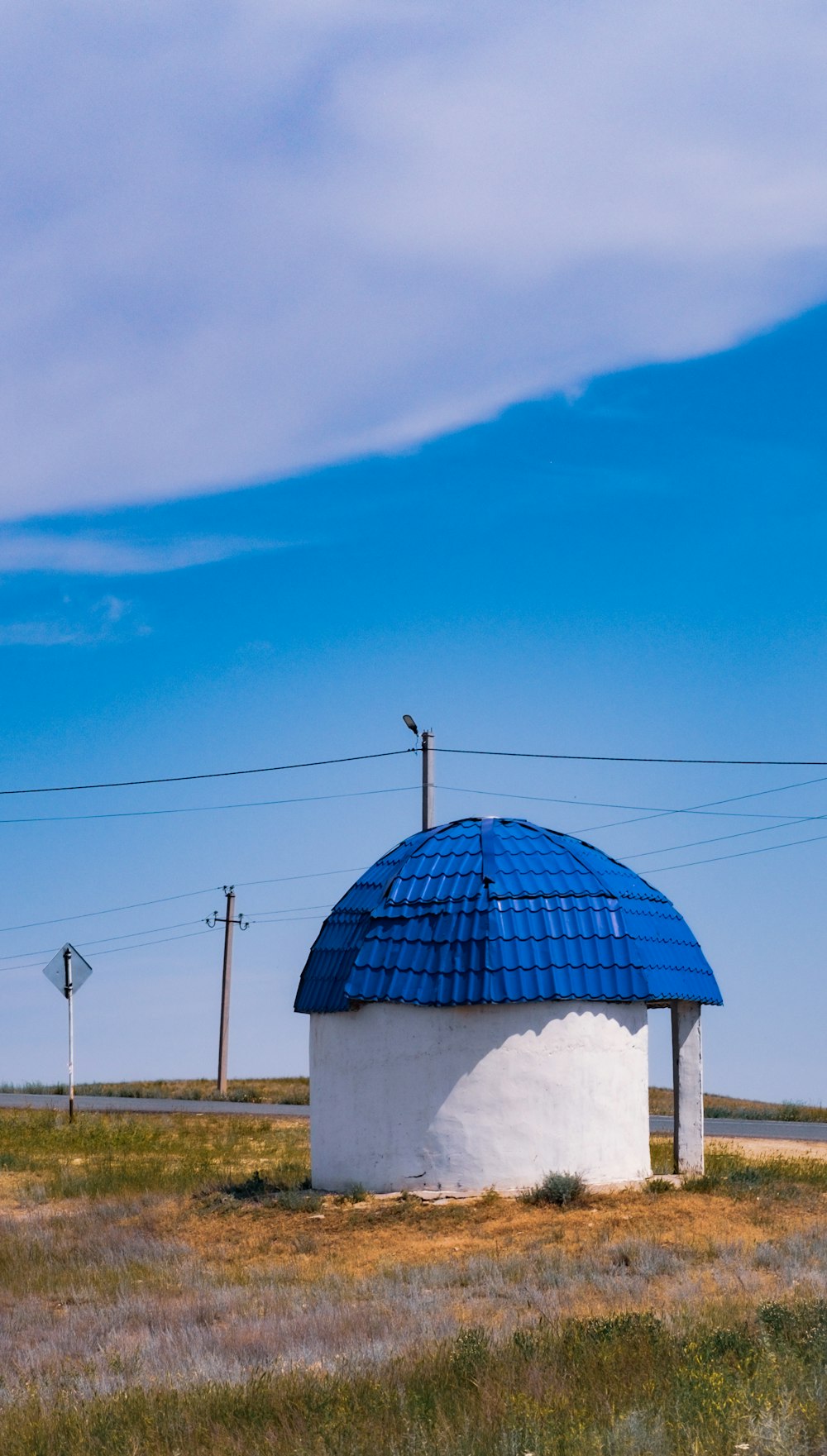 a round building with a blue roof in the middle of a field