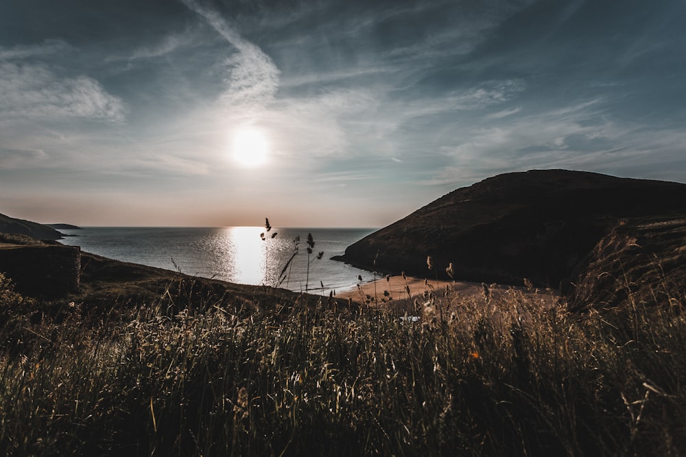 the sun is setting over the ocean with a boat in the water