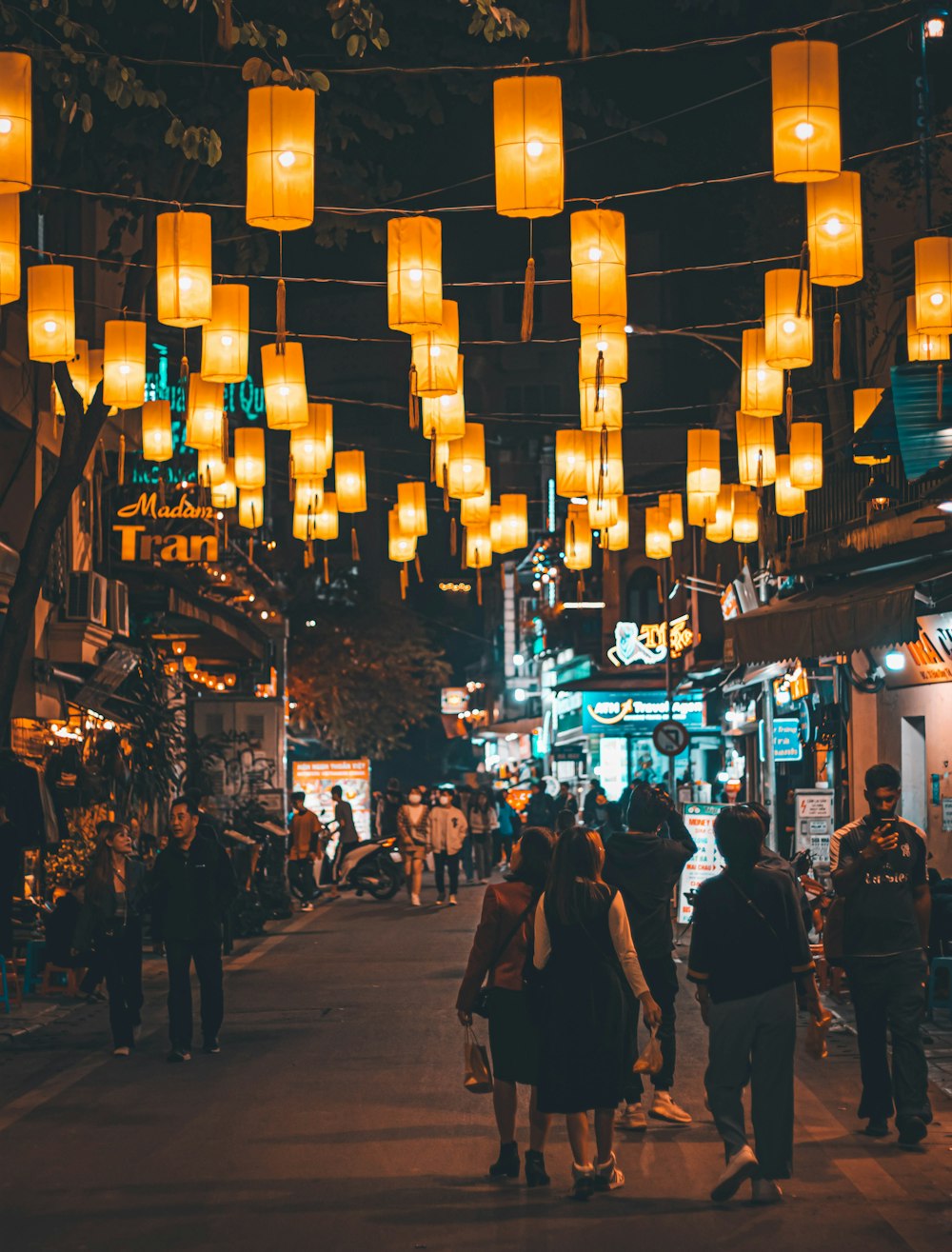 a group of people walking down a street next to tall buildings