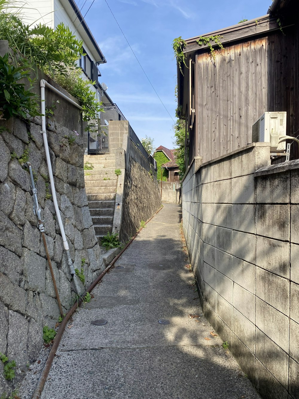 Un callejón estrecho con un muro de piedra y una escalera