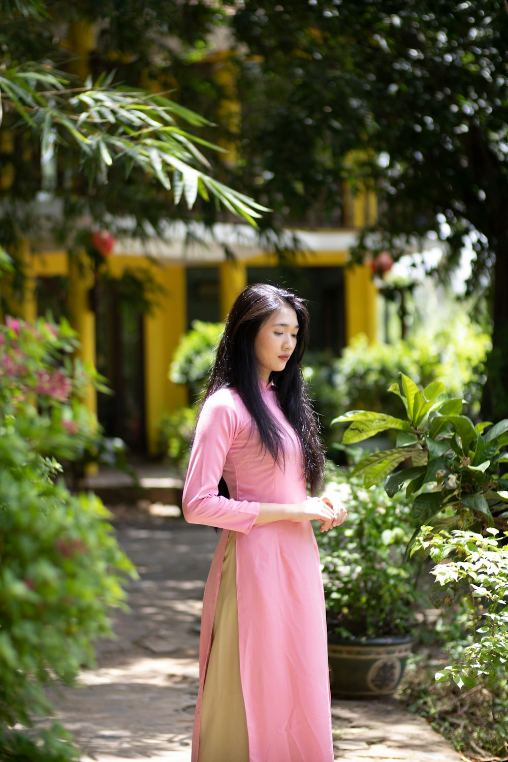 a woman in a pink dress standing in a garden