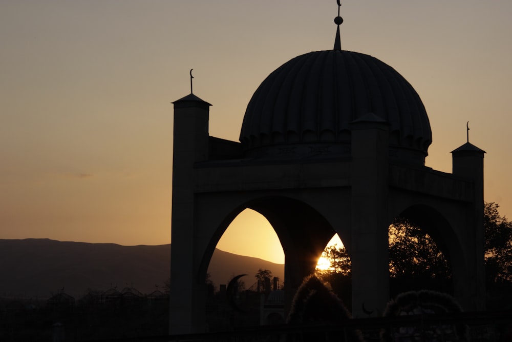 the sun is setting behind a large building