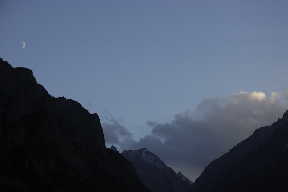 a view of a mountain with a half moon in the sky