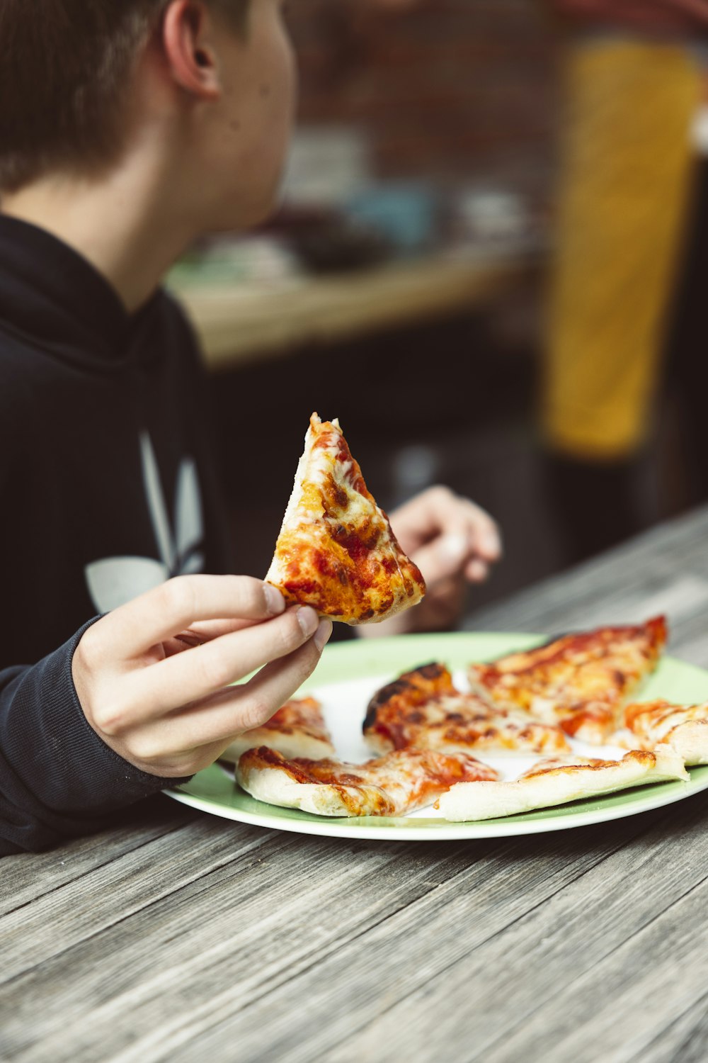 une personne mangeant une part de pizza dans une assiette