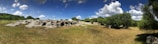 A panoramic view of the three Cuesta stones surrounded by cerrado vegetation under a clear sky.