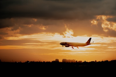 An airplane soaring above clouds during sunset, highlighting travel excitement.