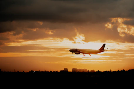A sleek Skysutra airplane soaring above clouds during a vibrant sunset.